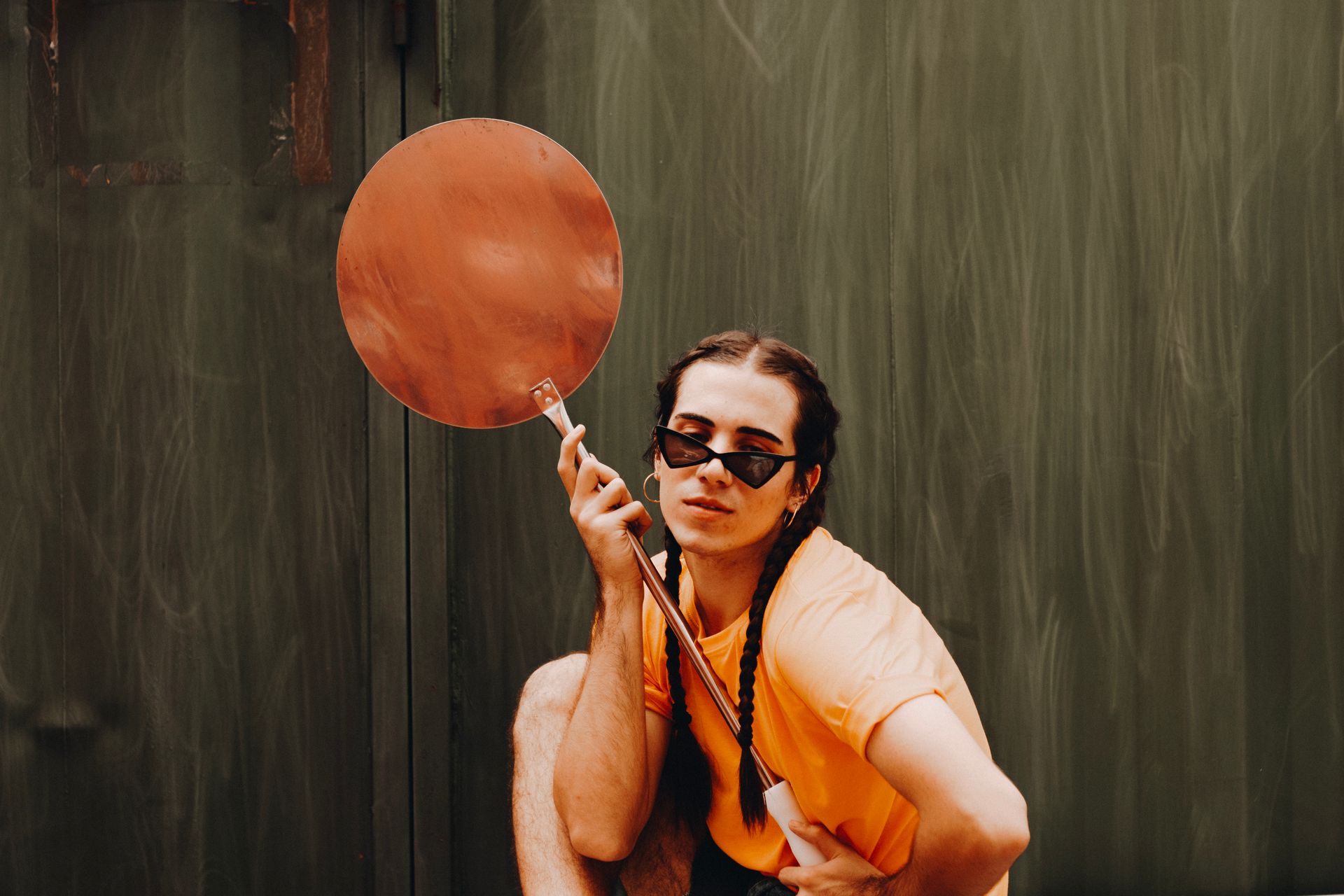Photo of Man in Orange T-shirt Holding Metal Object