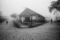 一张黑白照片，拍摄的是雾蒙蒙的街道，街上有两个人，背景是历史建筑