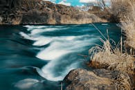 迷人的长曝光照片中，河流蜿蜒流过自然景观，四周环绕着岩石与干草