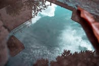 水坑中宁静地反射着云和树木，捕捉了城市的宁静