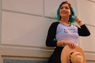 一位穿着随意、留着青色头发的女子在户外戴着遮阳帽微笑