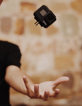 A creative shot of an action camera seemingly floating above an outstretched hand against a blurred background.