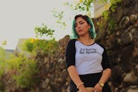 一位蓝发年轻女子穿着印有“我宁愿读书”字样的衬衫在户外摆姿势