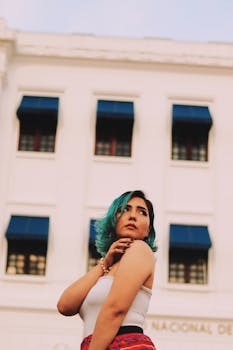 一位留着碧绿色头发的时尚女士，在经典建筑前自信地摆出姿势