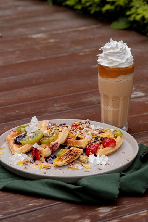 Free Savor a plate of waffles topped with fruit alongside a creamy iced coffee. Stock Photo