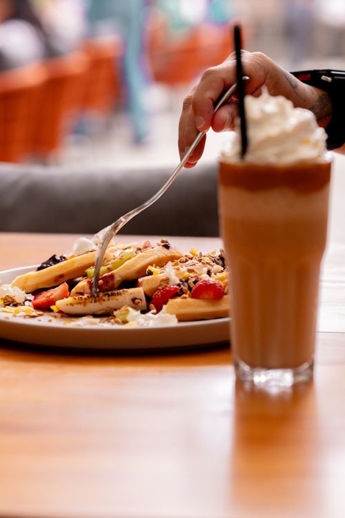 Free Close-up of waffles with fruit and iced coffee on a table at a café. Stock Photo
