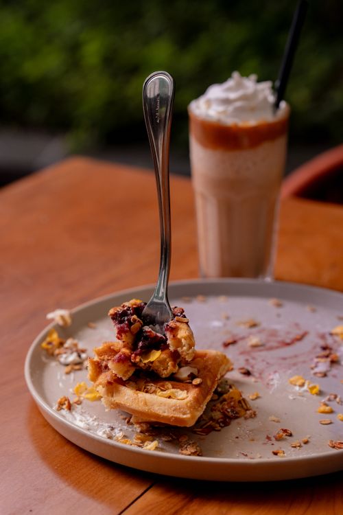 Free Close-up of a waffle with berries on a plate, accompanied by a whipped cream coffee drink. Stock Photo