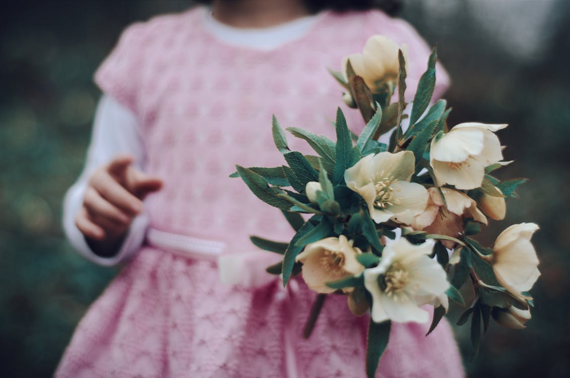 Selective Focus Photo of Girl Holding Flowers