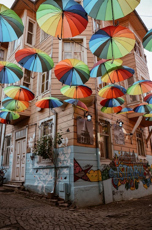 Multicolored Umbrella Hung Outside Brown Wooden House