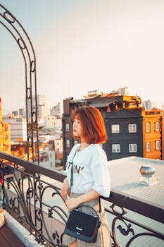 日落时分，一名年轻的东亚妇女在越南的城市屋顶上欣赏着周围的建筑景观