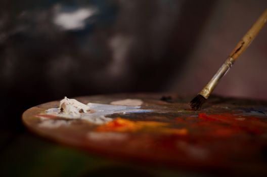 Close-up of an artist's palette with vibrant paints and a brush for creative expression.