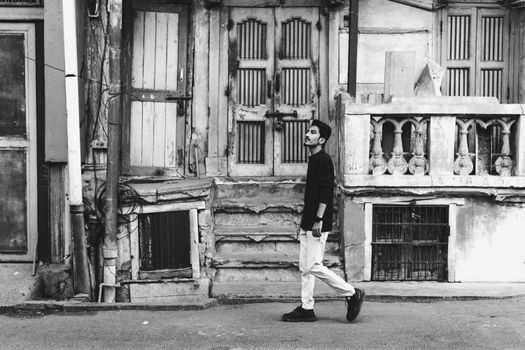 Black and white photo of a man walking past historic buildings in Ahmedabad, India.