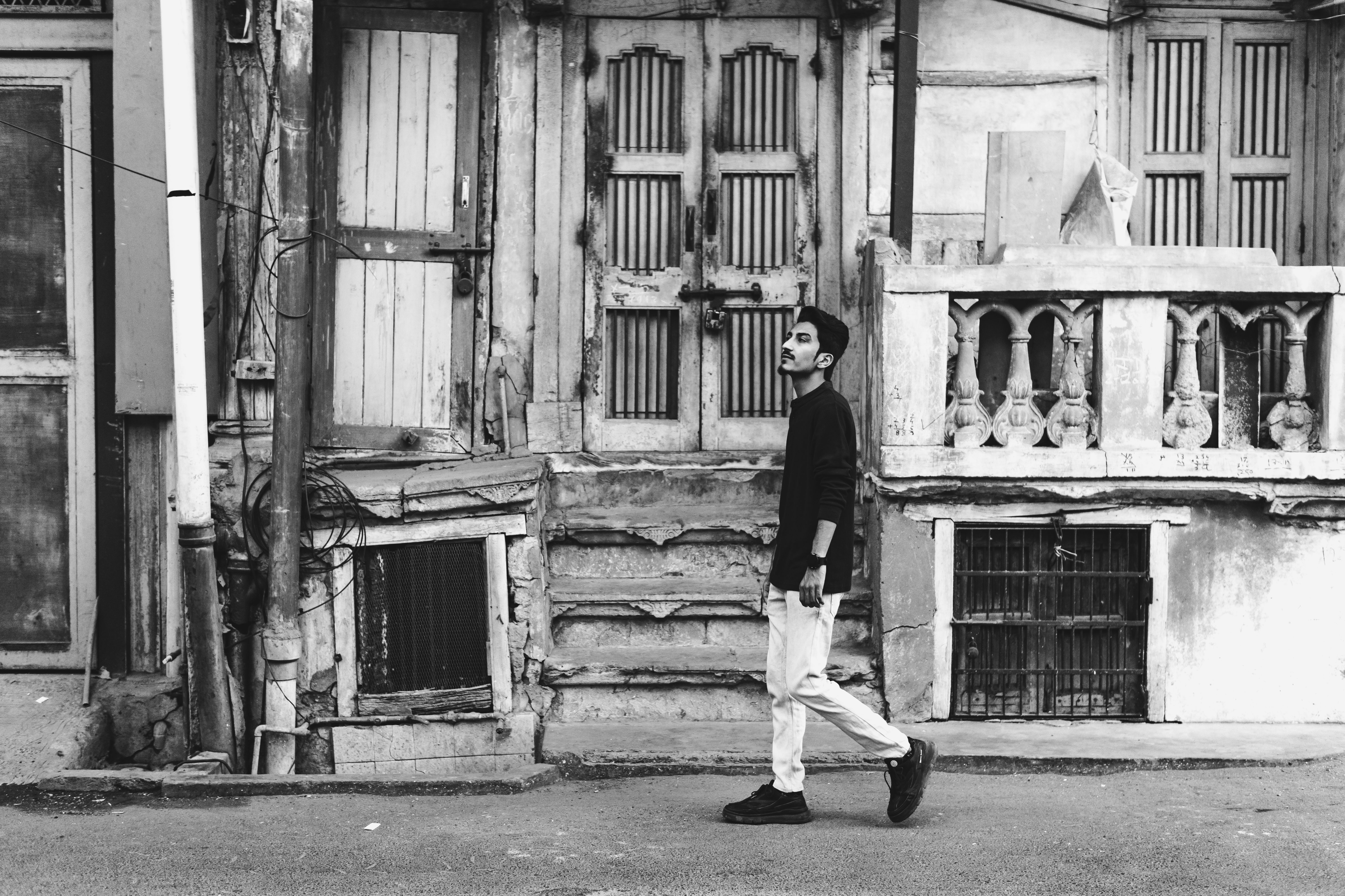 A black and white photo of a man walking down the street · Free Stock Photo