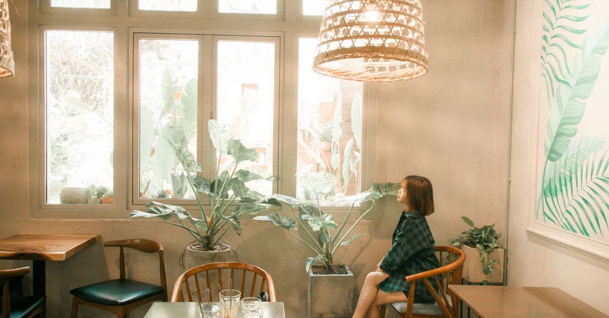 woman sitting at a table looking tired at afternoon light streaming through window