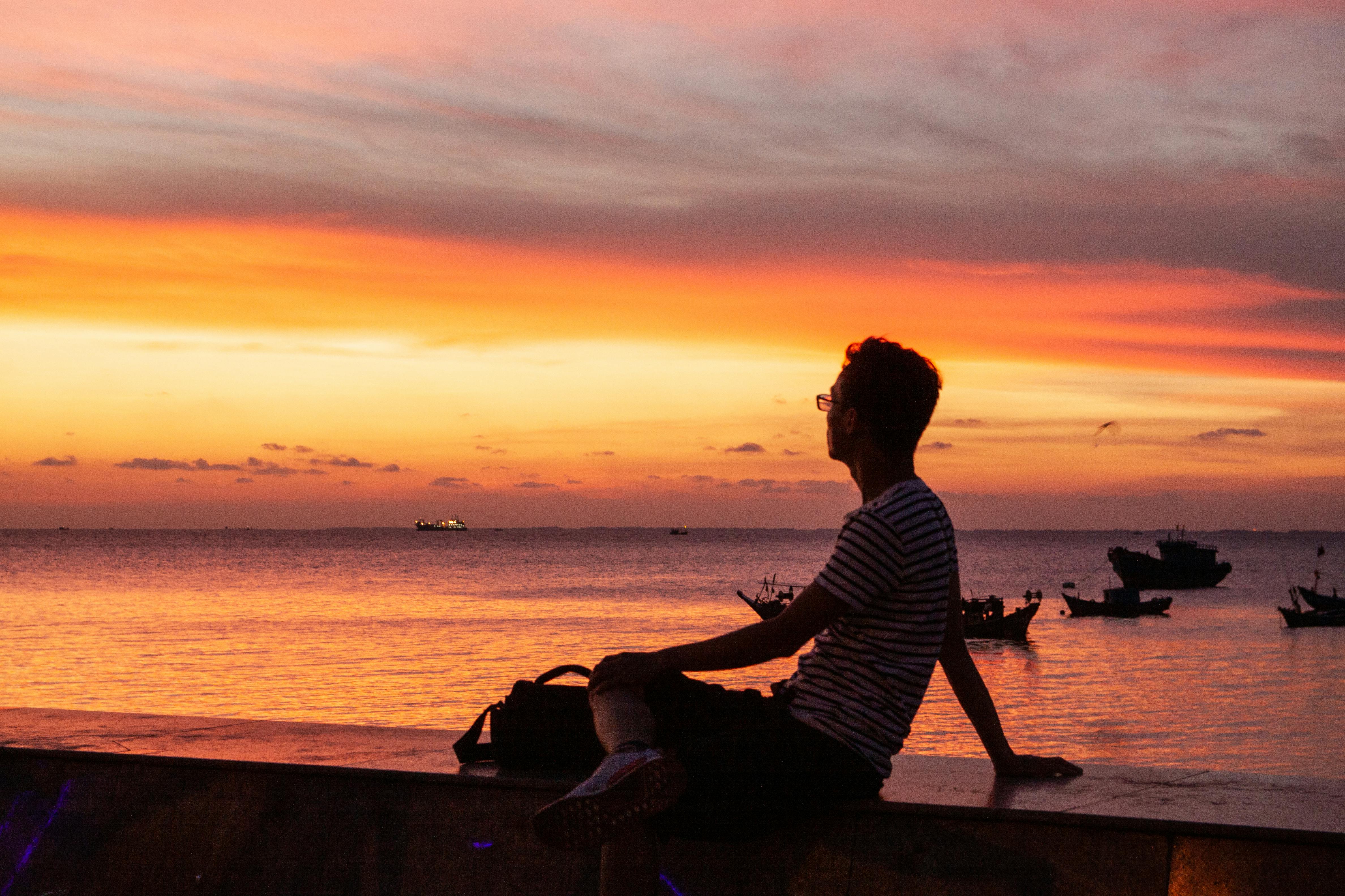 A Man Sitting on the Seawall at Night · Free Stock Photo