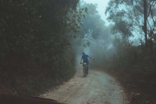 Person Riding Bicycle on Dirt Road