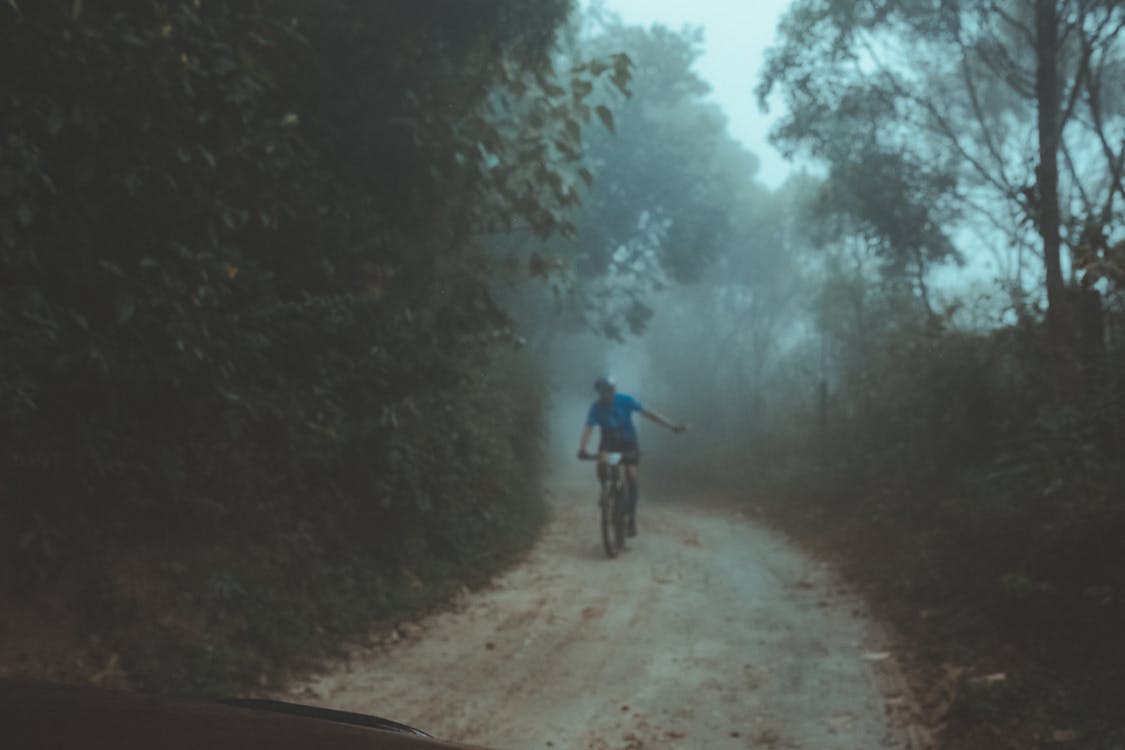 Person Riding Bicycle on Dirt Road
