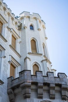 Close-up of a Gothic Revival-style castle tower with arched windows and crenellations.