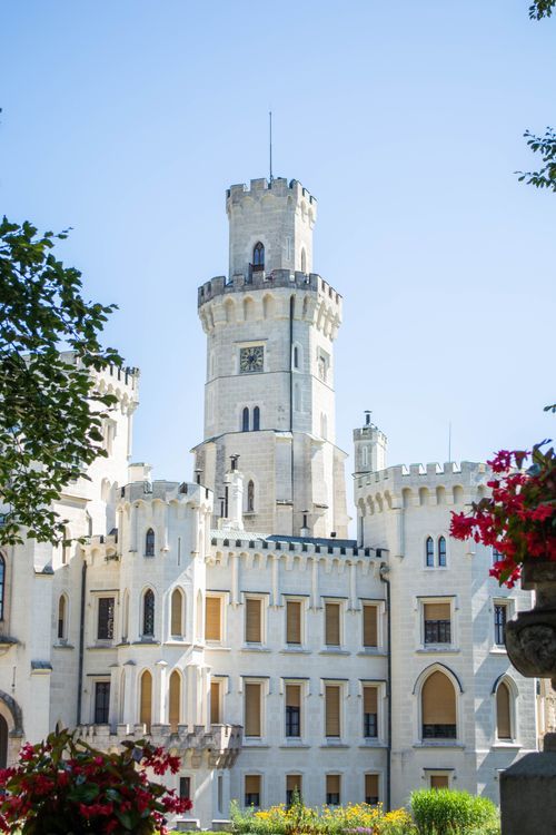 Free A beautiful historic castle with a floral foreground under a clear blue sky. Stock Photo