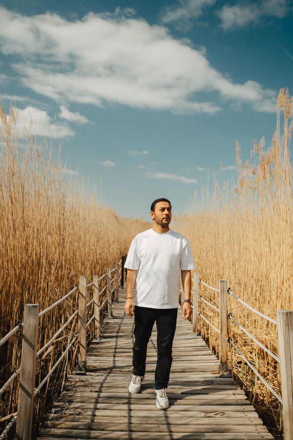 Man walking a wooden boardwalk through tall reeds — photo by Musa Ortac on Pexels