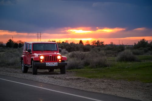 красный внедорожник Jeep рядом с дорогой