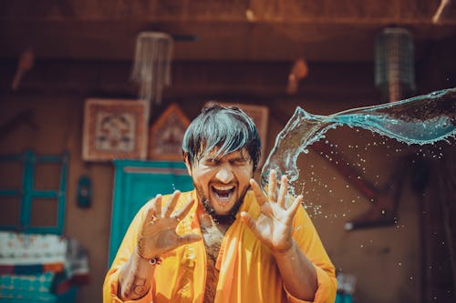 Person Throwing Water On Man In Yellow Top