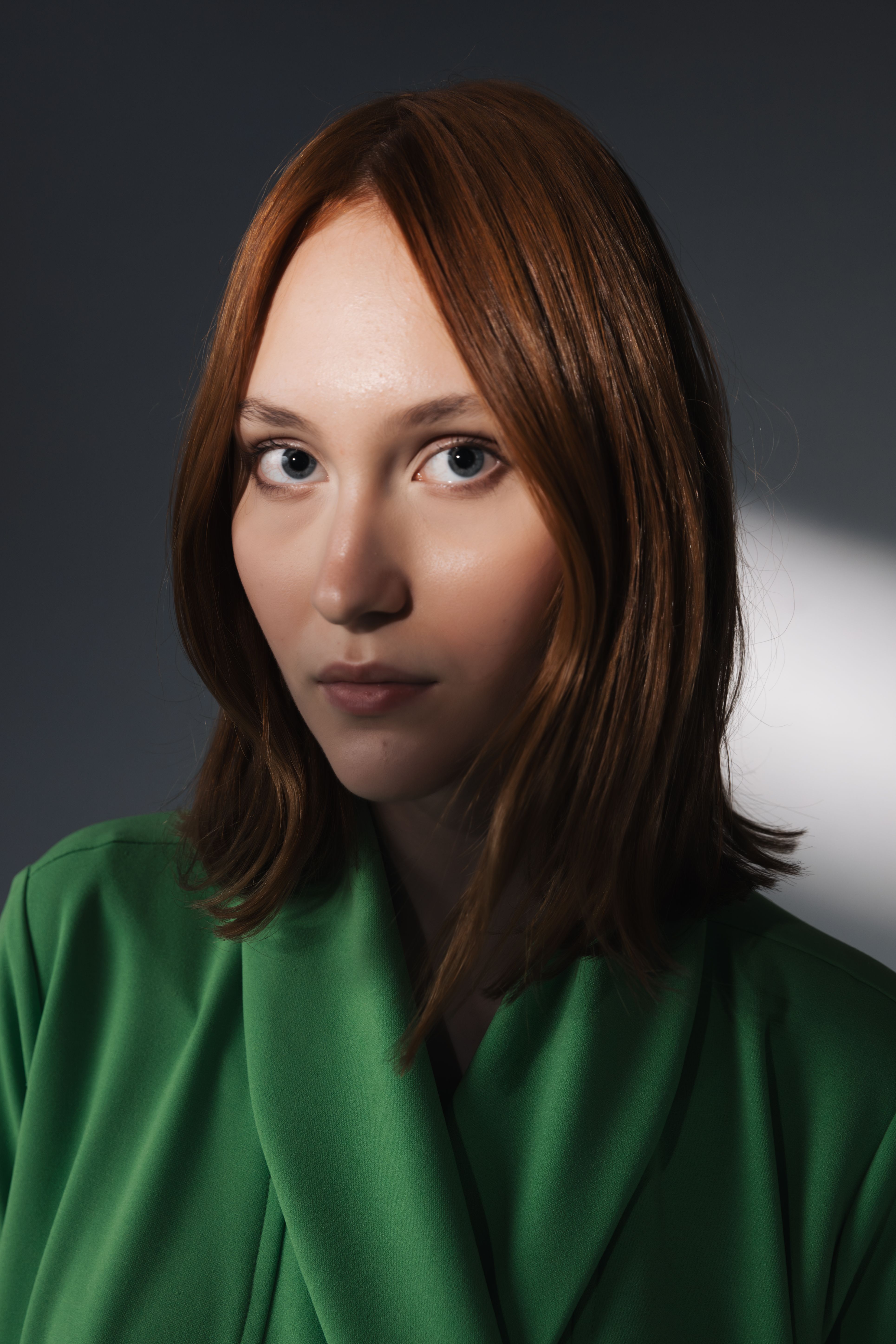 Studio portrait of a woman with brown hair wearing a green robe, showcasing fashion elegance.