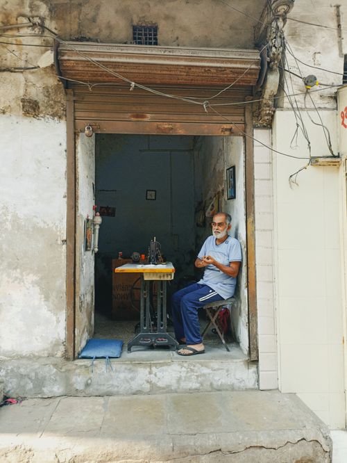 Free An elderly man using a sewing machine in a rustic workshop in Ahmedabad, conveying traditional craftsmanship. Stock Photo