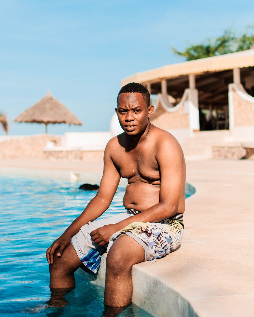 A man enjoying summer relaxation by the poolside under a clear sky.
