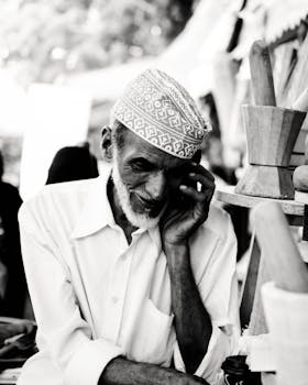 一位穿着传统服装的老人，在户外陷入沉思，被拍摄成黑白影像