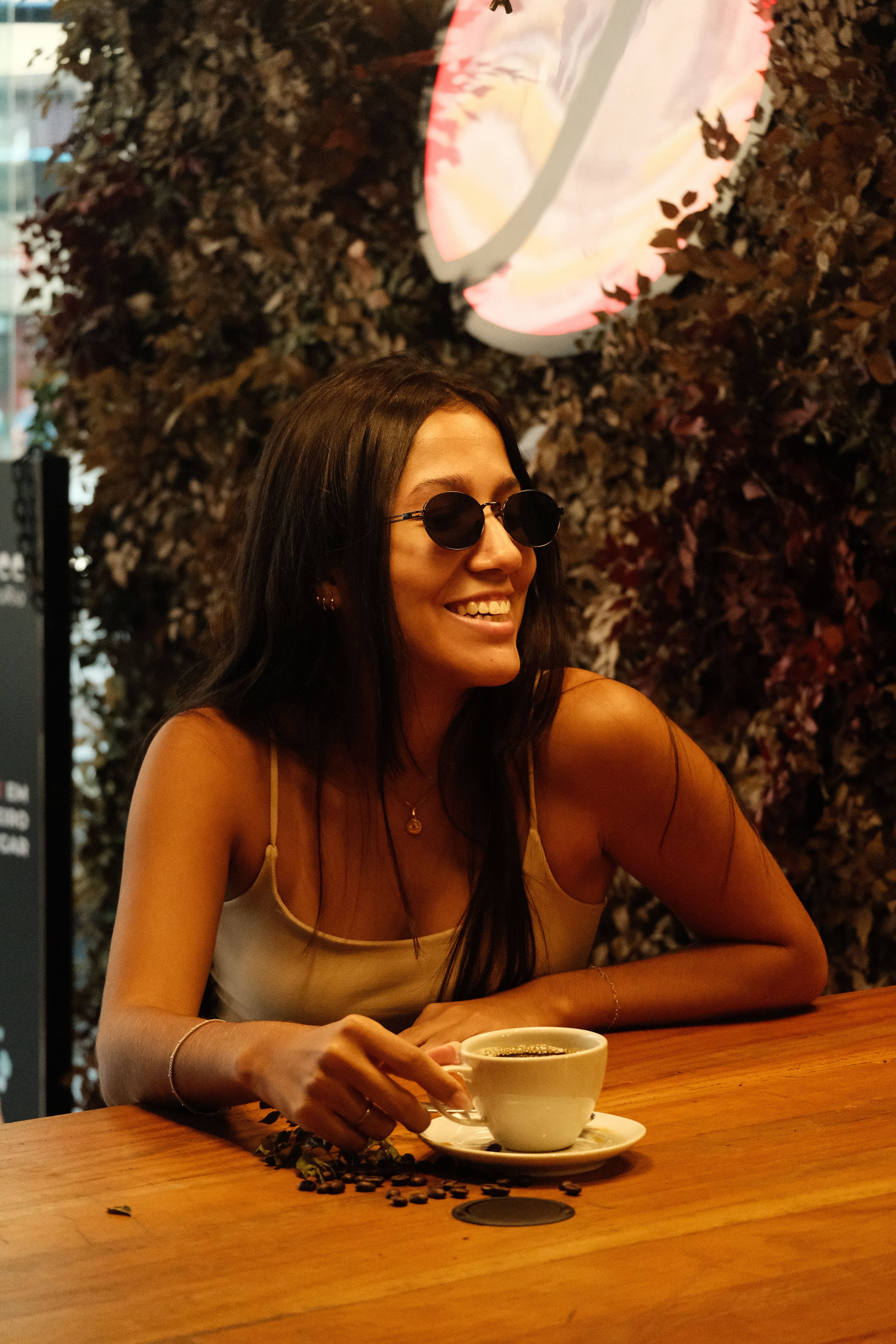 Woman in sunglasses smiling while enjoying coffee at a cafe in Rio de Janeiro.