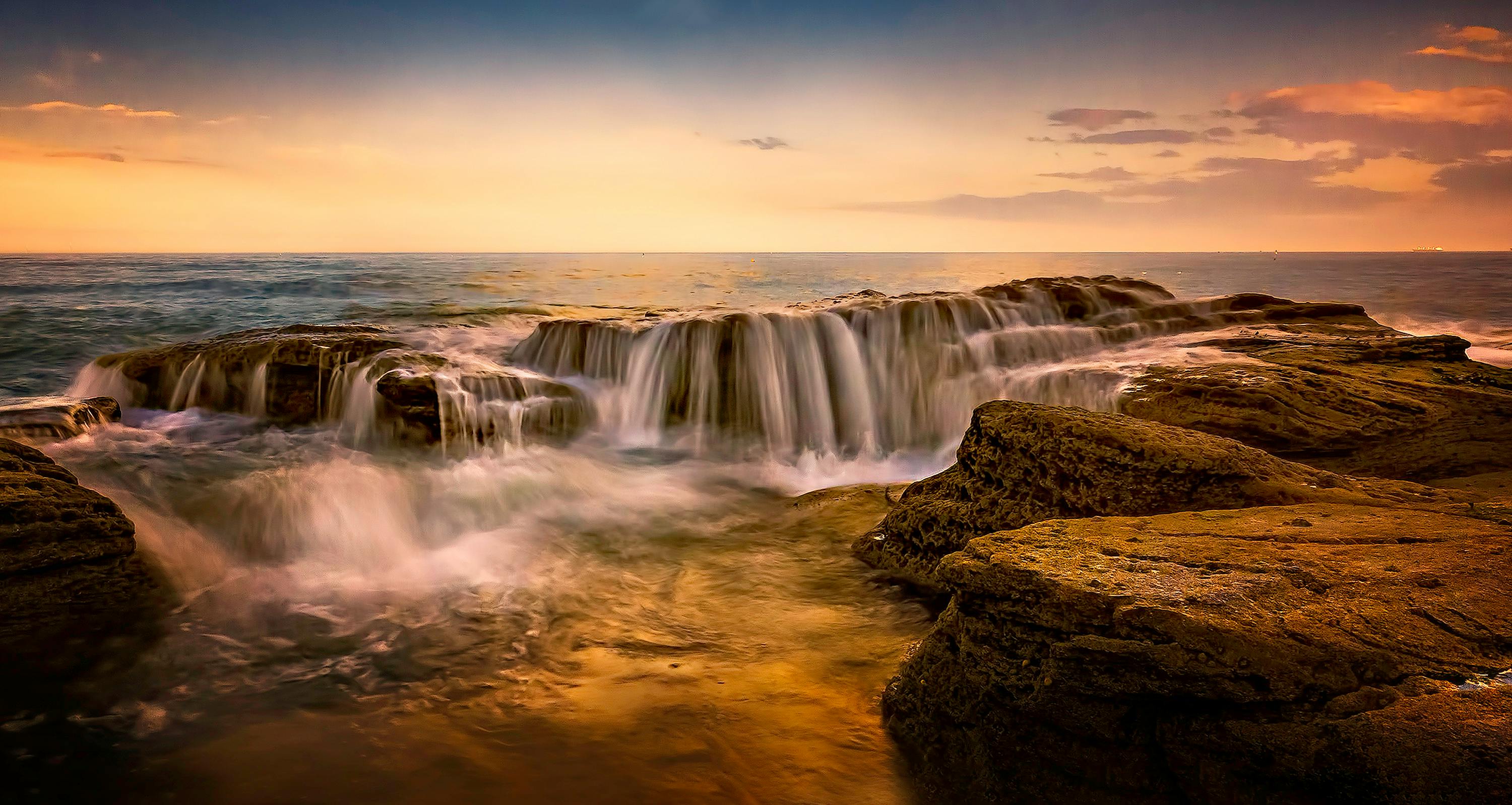 日落时分，海浪从岩石上倾泻而下，景色壮丽，营造出宁静的景观