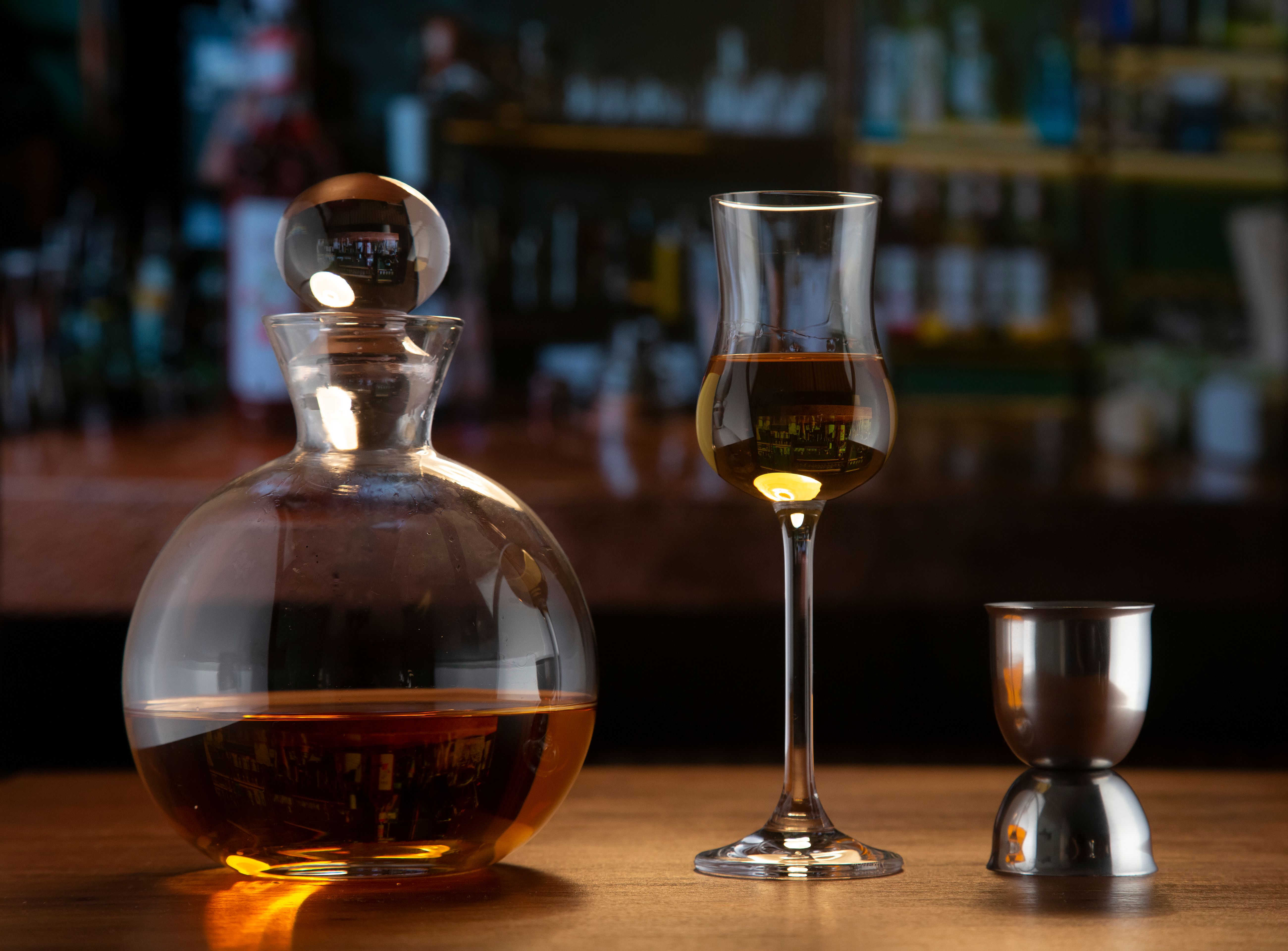 An elegant setup featuring a glass decanter with brandy and a glass on a bar counter.