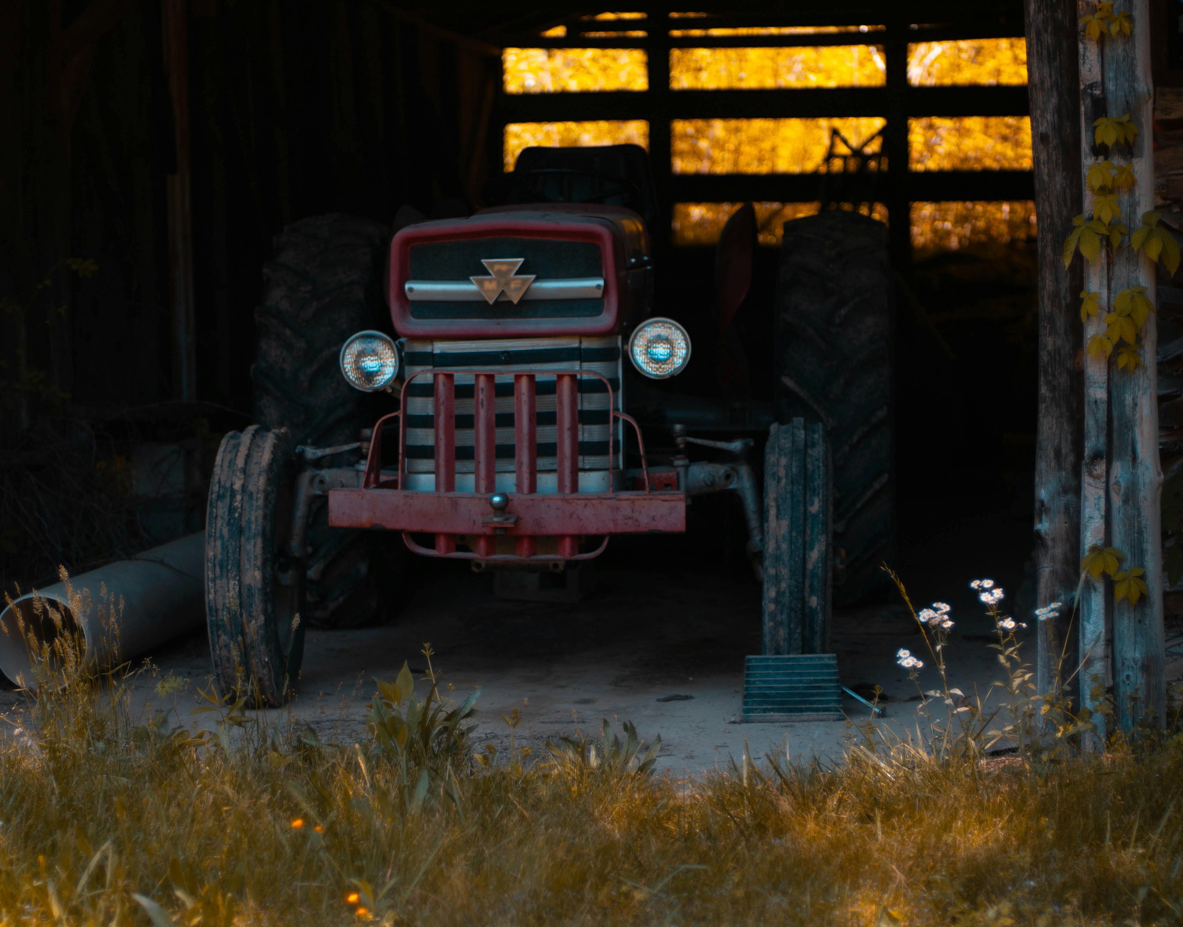 An old tractor is parked in a barn · Free Stock Photo