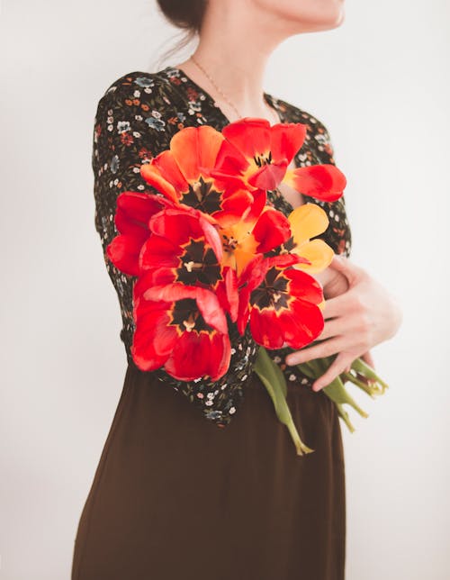 Женщина держит красные цветы