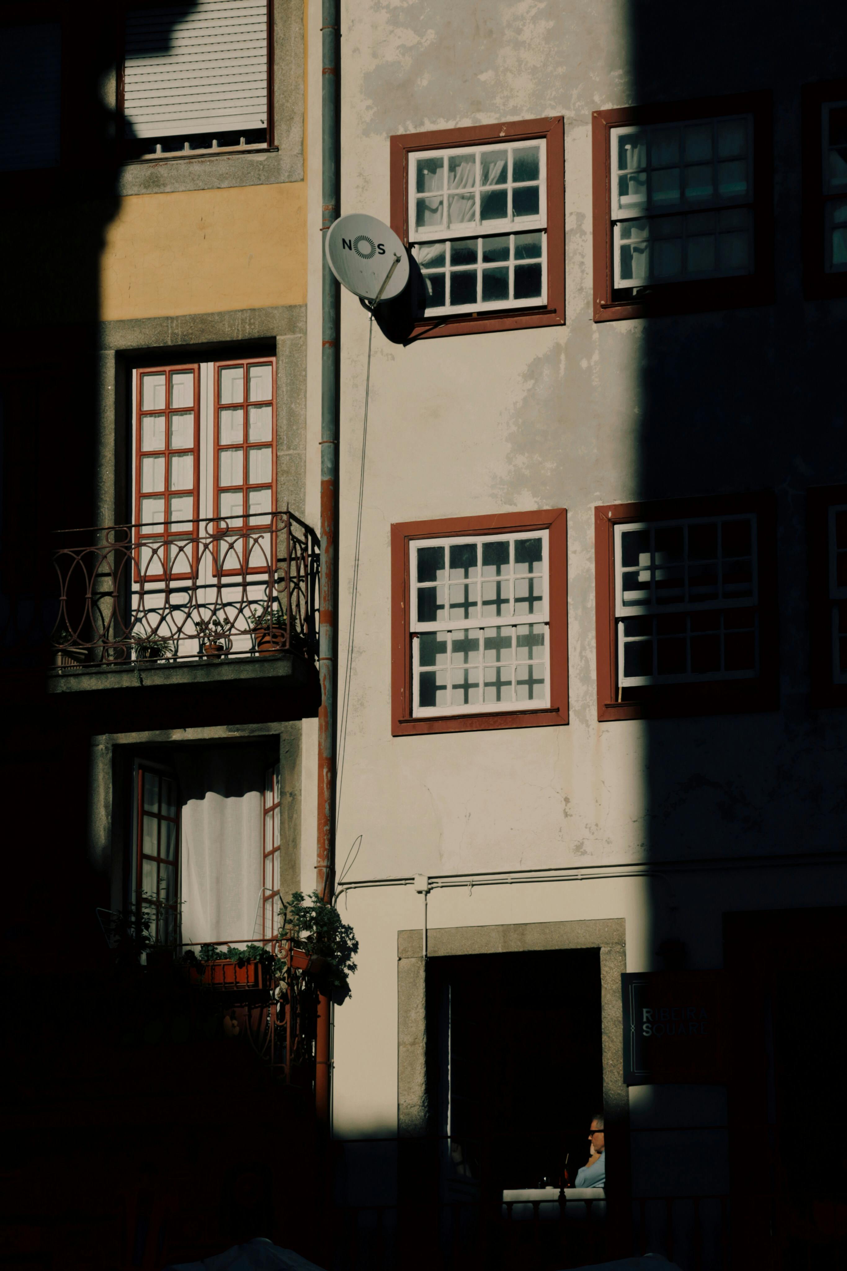 Urban street scene in Porto with sunlight casting dramatic shadows on a residential building.