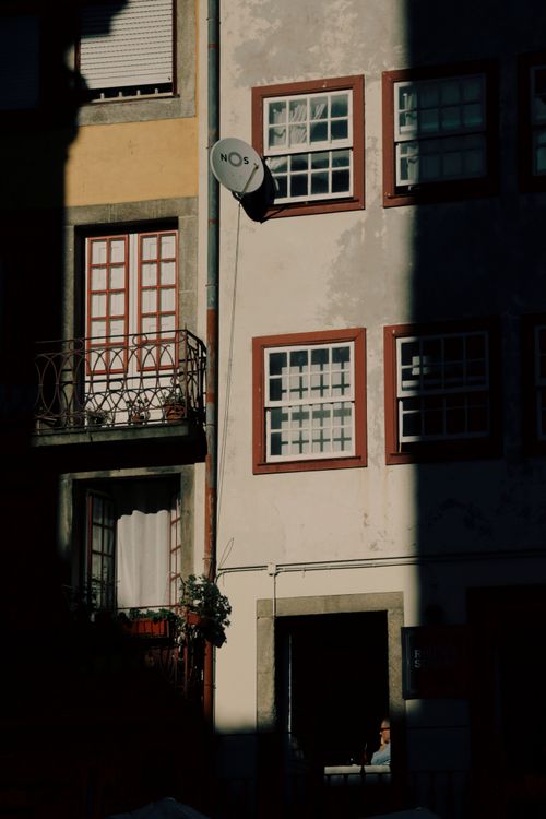 Free Urban street scene in Porto with sunlight casting dramatic shadows on a residential building. Stock Photo