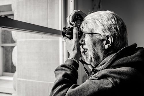 An older man is taking a photo of a window