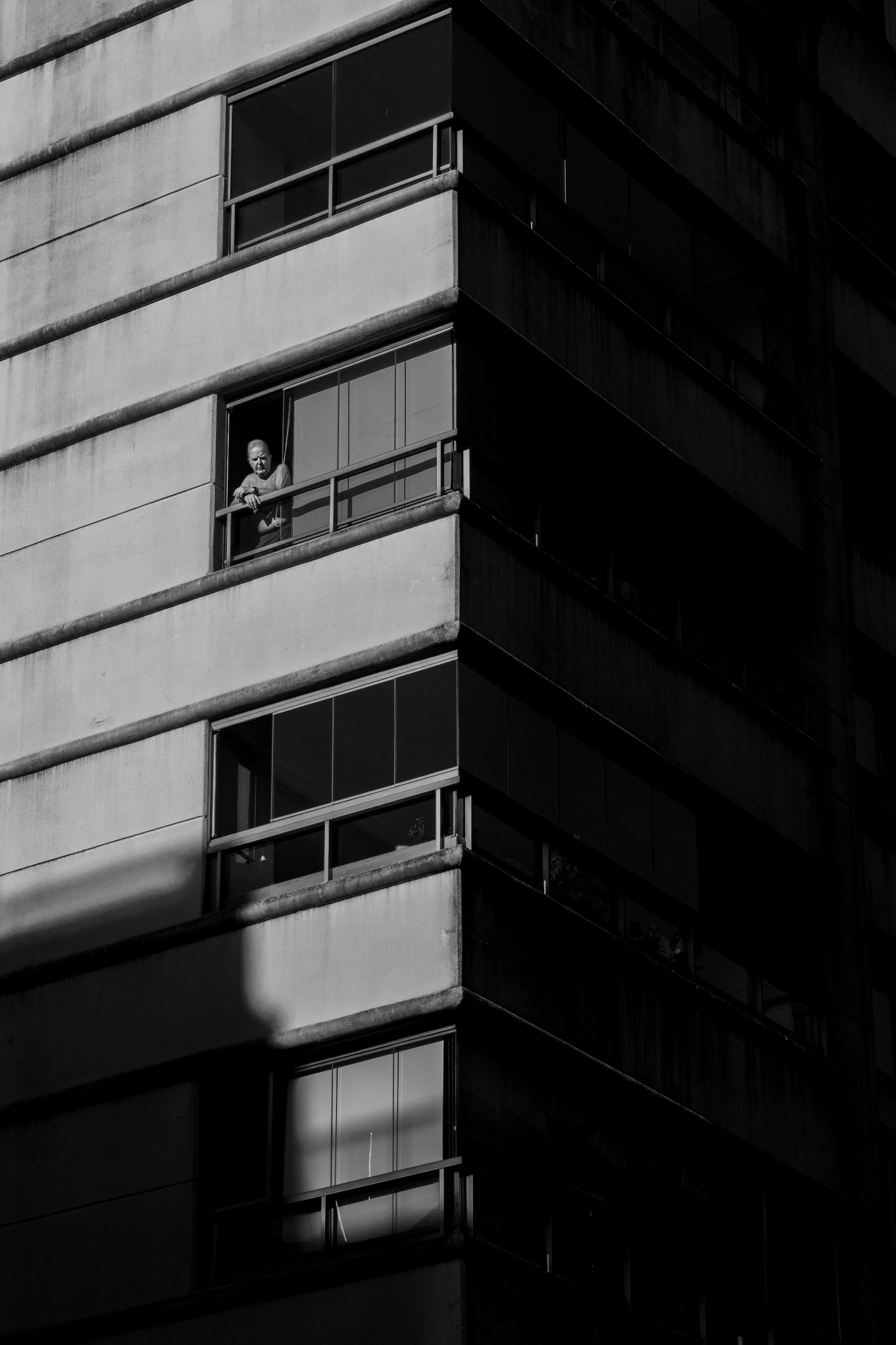 Black and white urban scene with a person in a Buenos Aires apartment window.