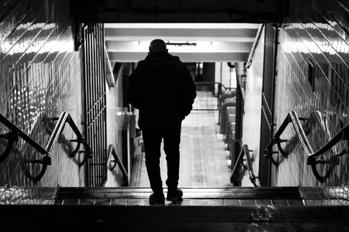 Free A striking black and white photo of a man descending stairs in a Buenos Aires subway station. Stock Photo