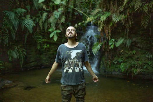 一个人快乐地站在郁郁葱葱的森林里，瀑布旁，拥抱大自然的宁静