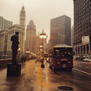 芝加哥市中心雨天的场景，展现了城市建筑、公共汽车和天际线的风貌