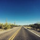 在亚利桑那州晴朗的蓝天下，空旷的沙漠高速公路两旁长满了仙人掌