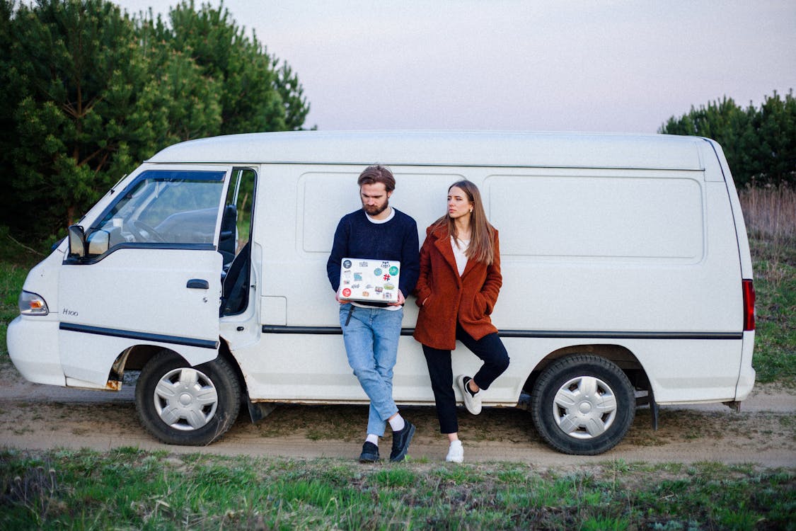 Free Woman and a man leaning on a White Van Stock Photo