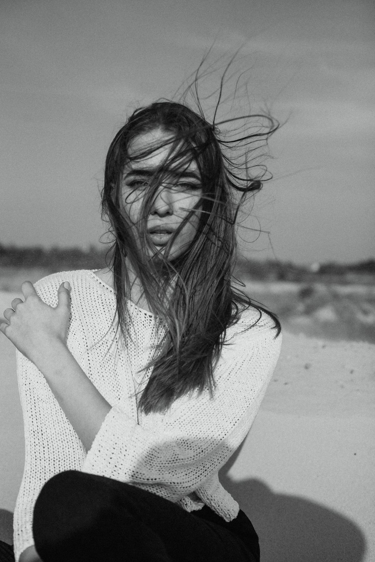 A woman in a white knit sweater sitting — the summer knit against bare skin