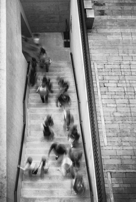 Blurred black and white capture of people moving on a Hong Kong stairway.