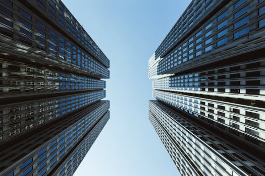 A majestic low angle view of skyscrapers reaching into a clear blue sky, showcasing urban architectural beauty.