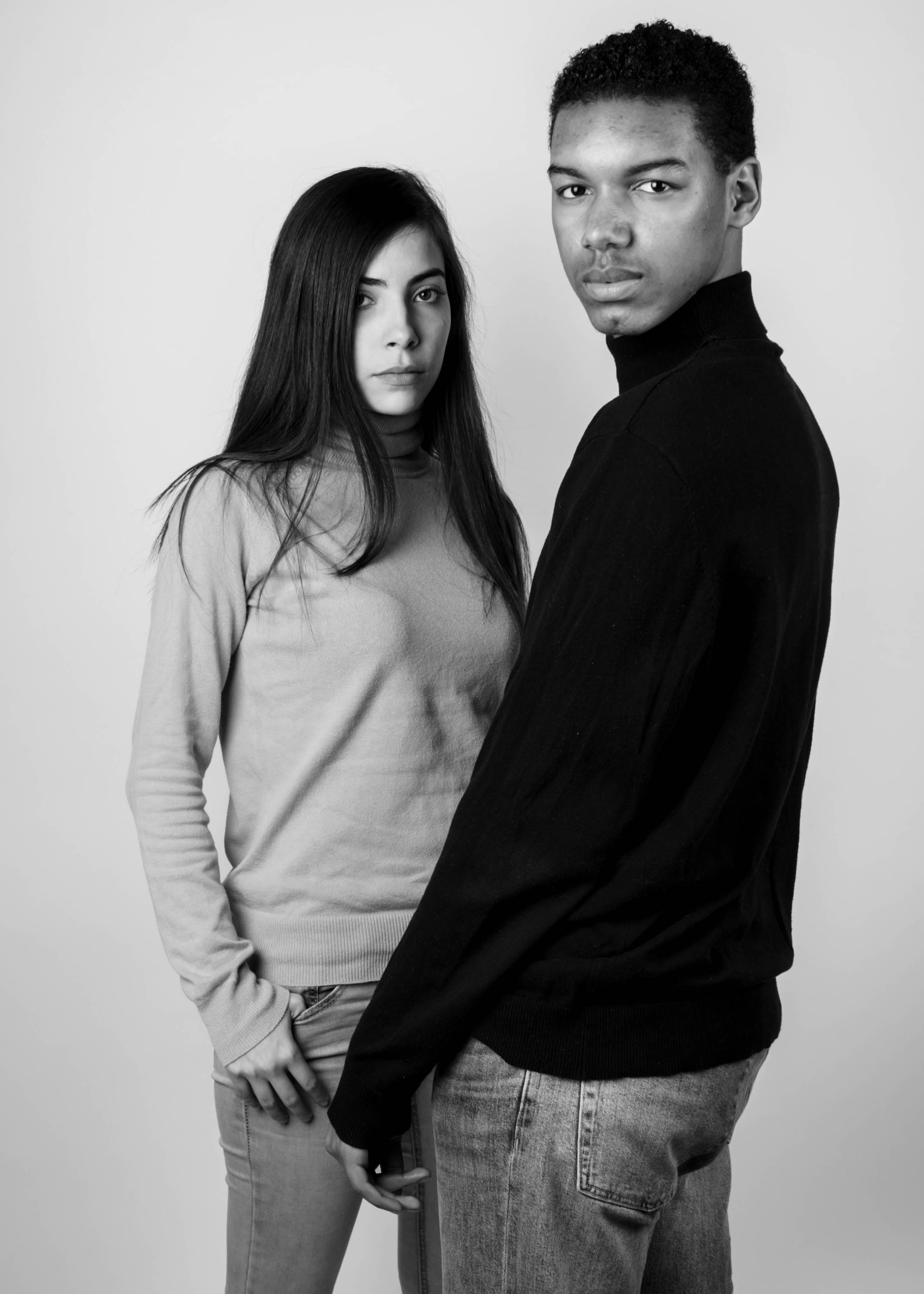 grayscale photography of standing man and woman wearing turtleneck long sleeved shirts