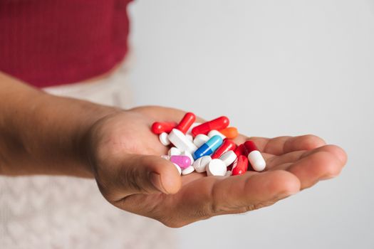 A person holding a handful of pills in their hand