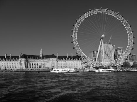 A monochrome cityscape view of the London Eye and surrounding architecture from the waterfront.